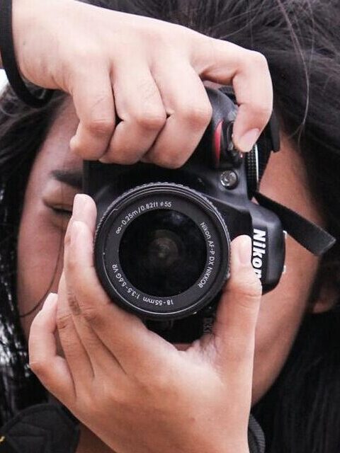 Portrait of a young female photographer capturing moments at the beach.