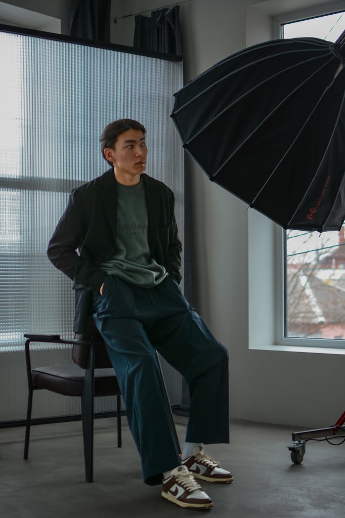 Man in modern photo studio with lighting equipment, relaxed pose.