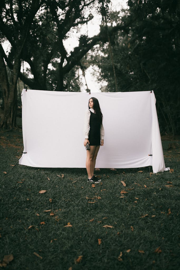 Woman posed in outdoor photoshoot with a forest scene backdrop.
